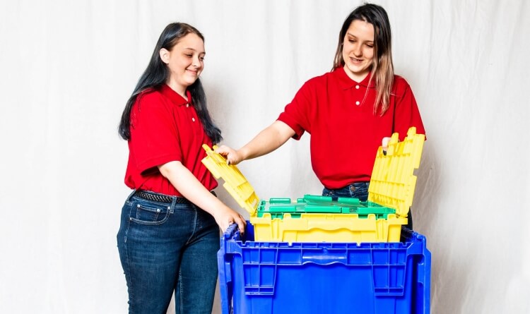 Two girls showing the three sizes of crates